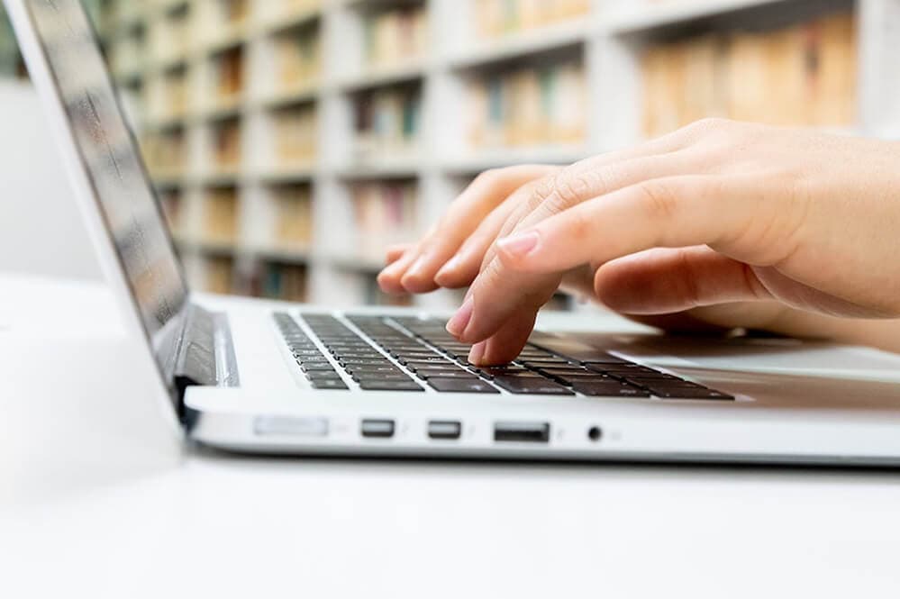 Woman typing up a blog post on her laptop