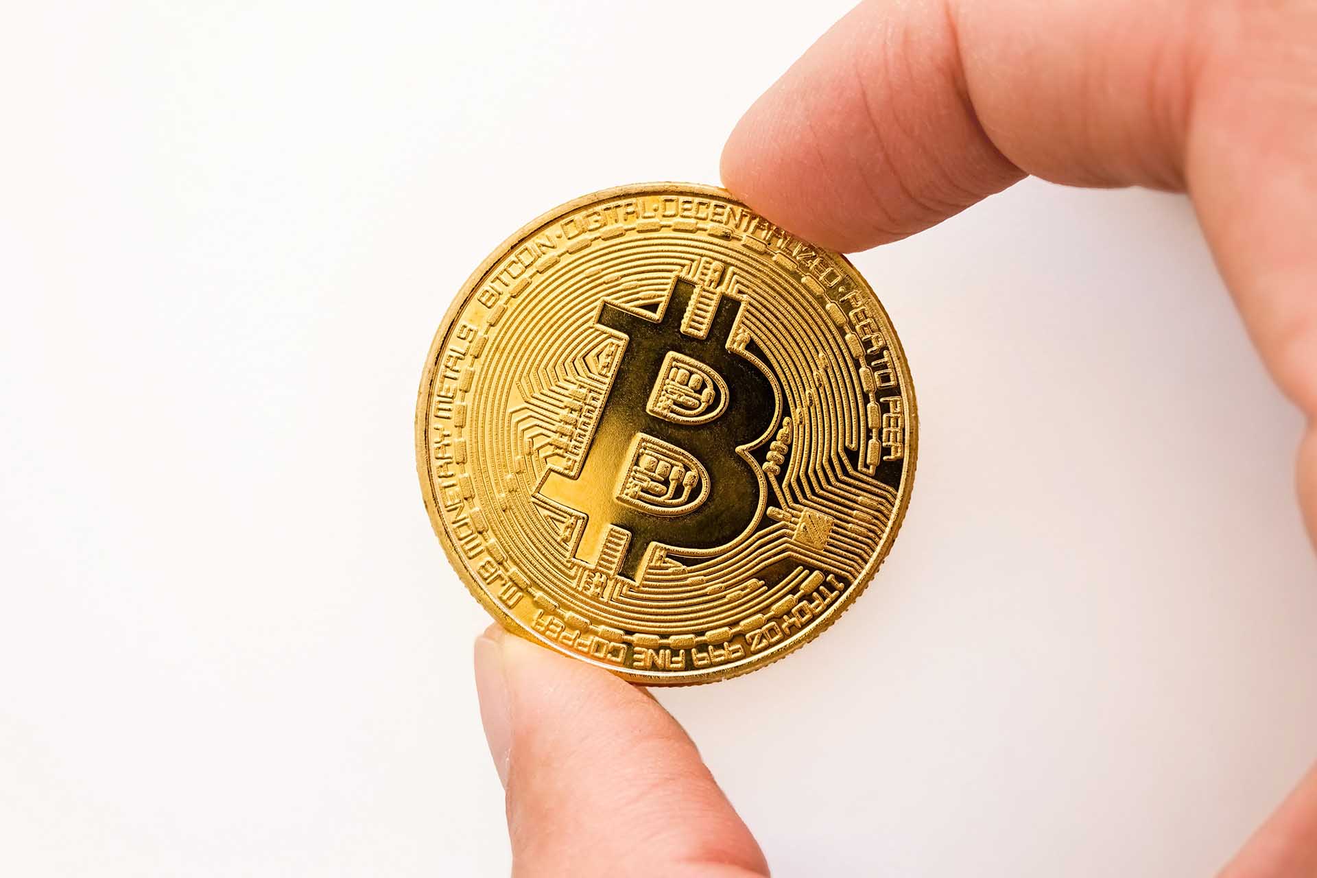hand holding a physical bitcoin made of gold