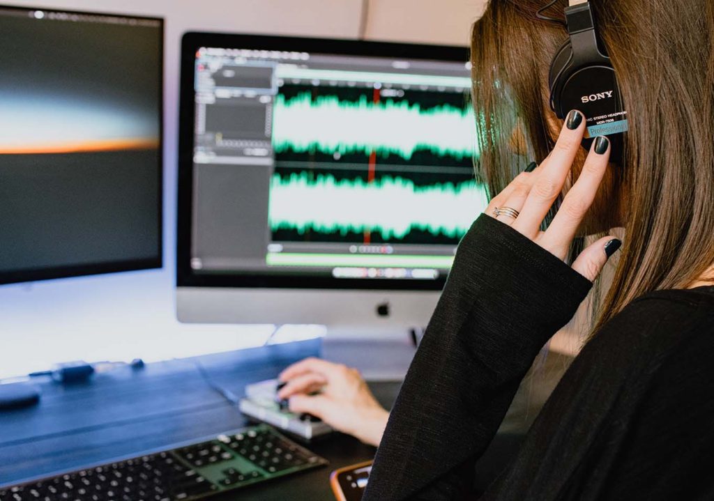 Woman doing audio production with headphones in a small studio