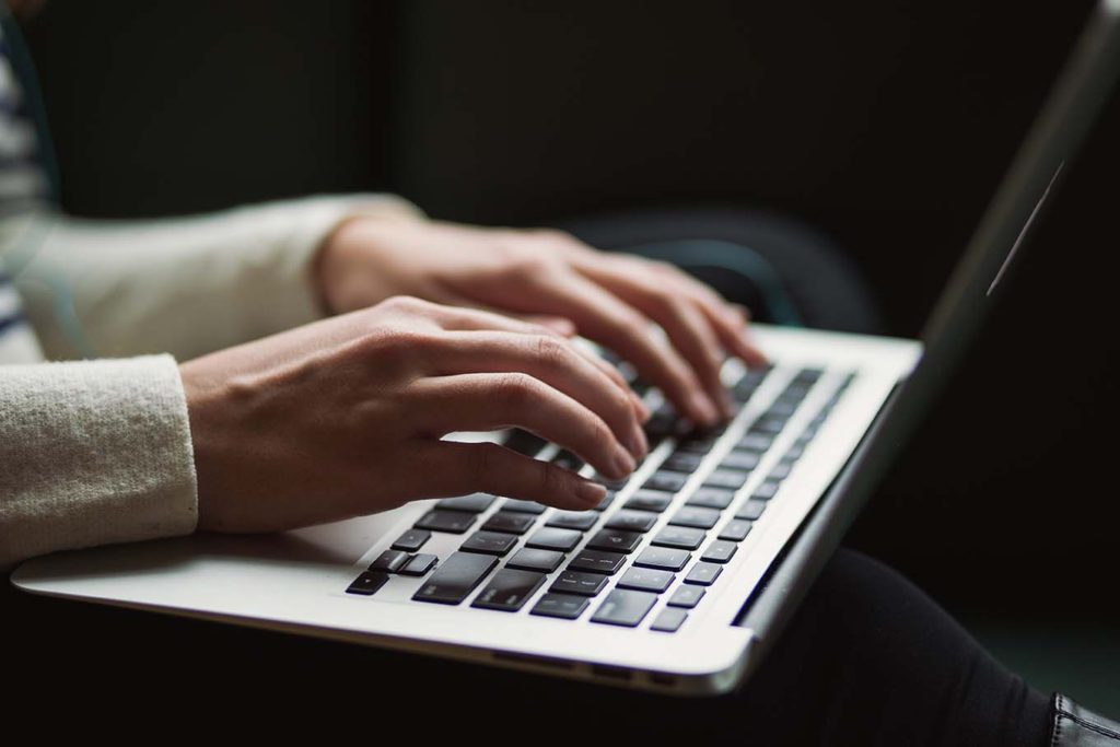 Woman writing a new blog post on her Macbook Pro